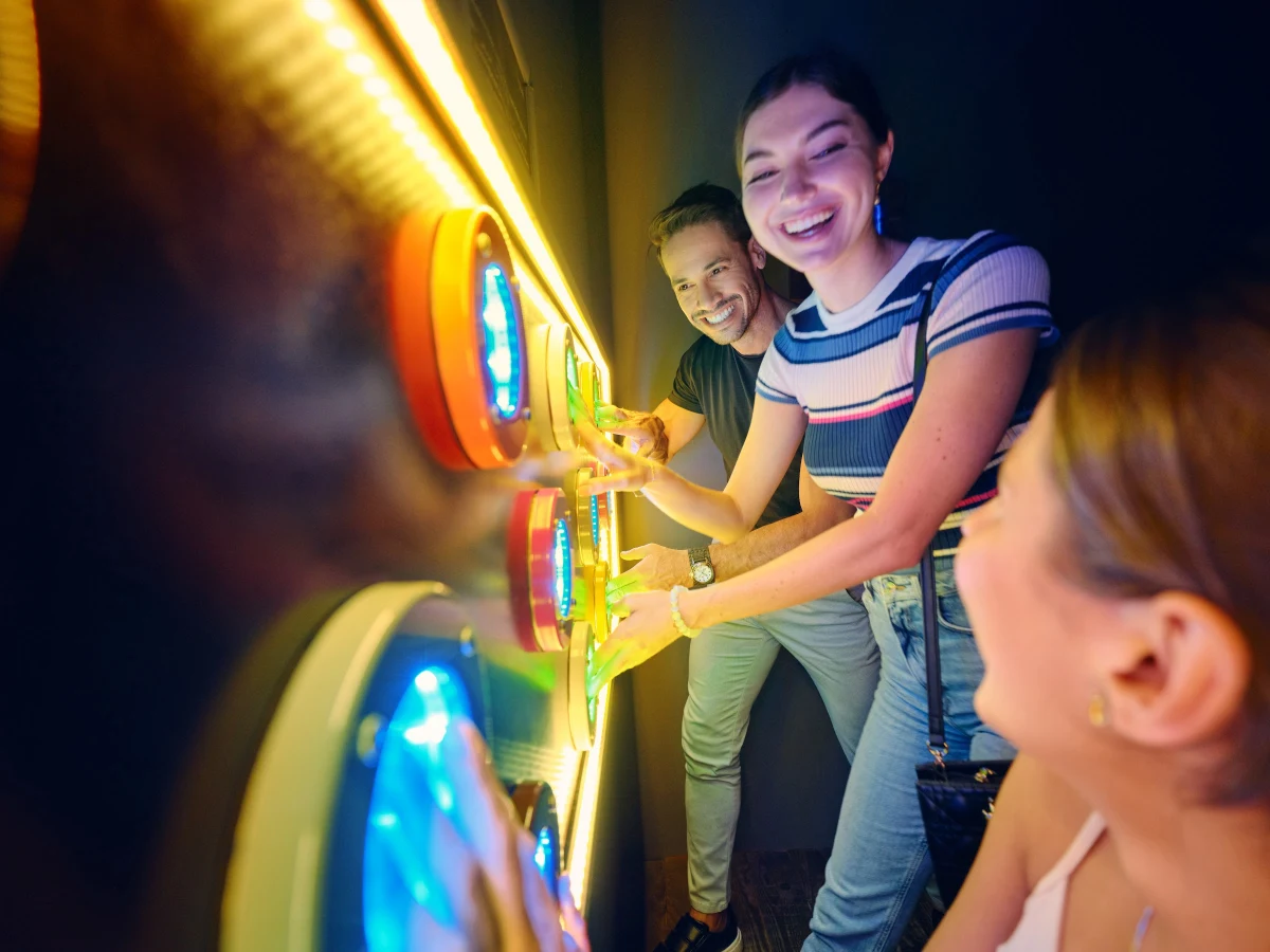 Friends laughing while playing a glowing light wall game at TEPfactor Dubai
